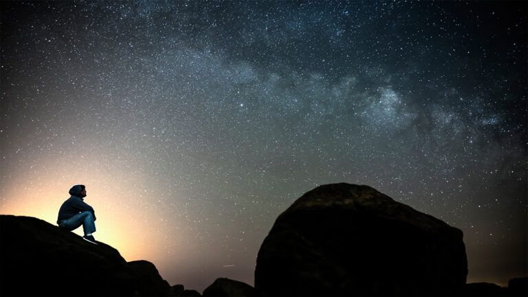 A boy gazes up at a starry sky