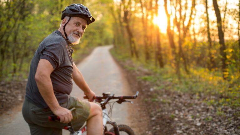 An older man getting ready for a morning bike ride in the woods.