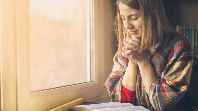 A young woman praying over a Bible.