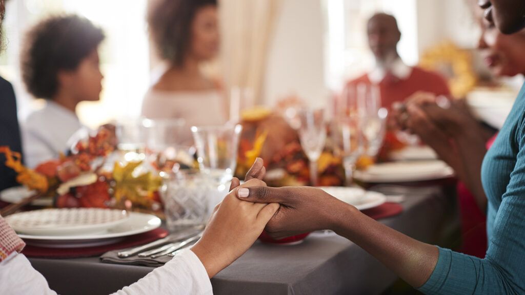 Family saying grace at Thanksgiving dinner table