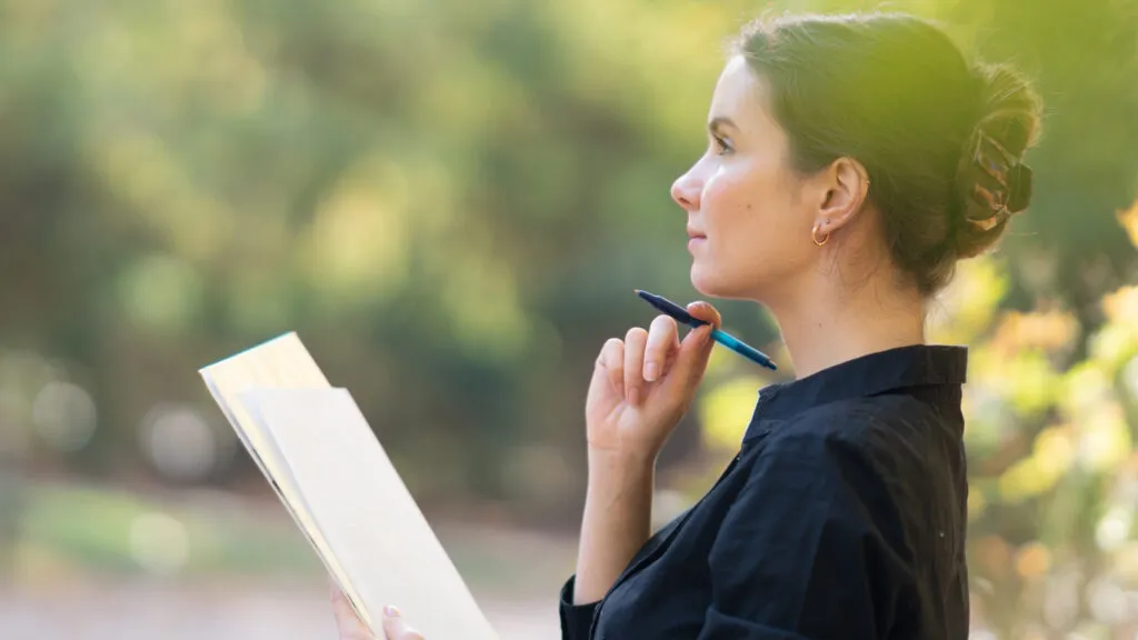 A young woman making a list outside.