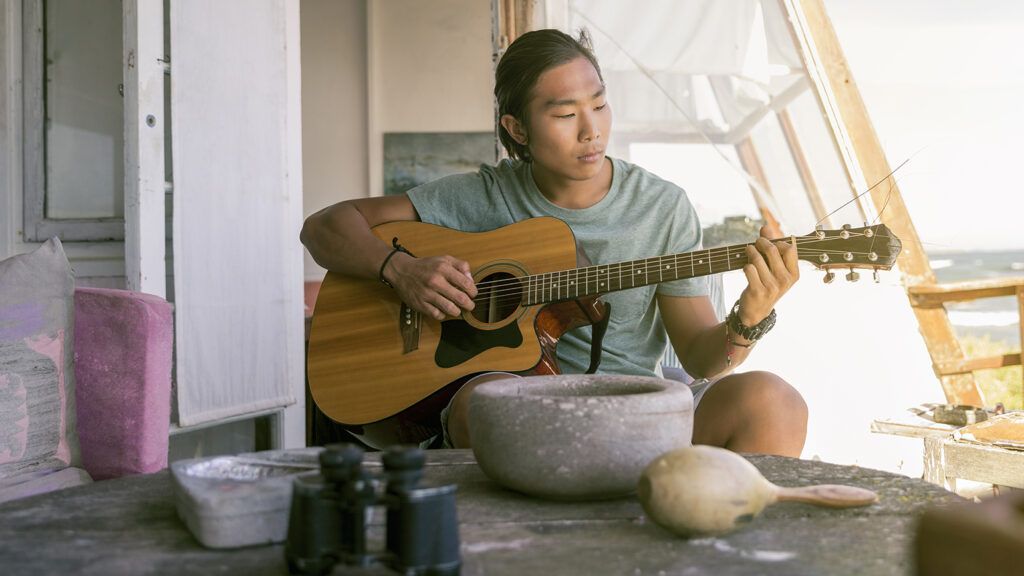 A man strums his guitar and sings