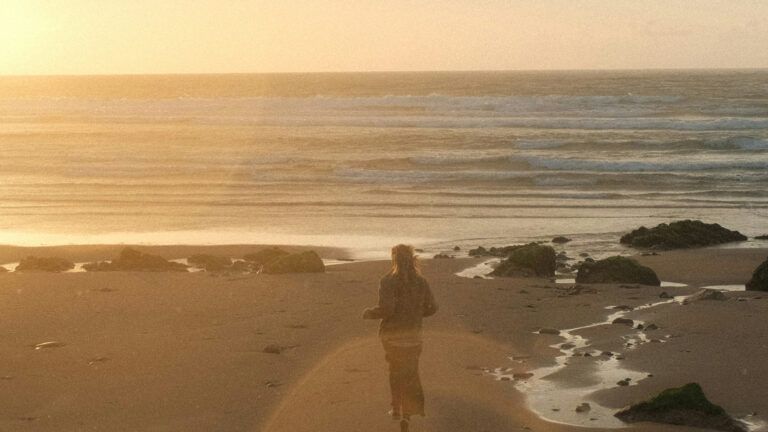 A woman standing on a beach during golden hour. Credit: Unsplash