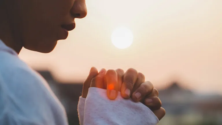 A woman praying at sunset for the spiritual benefits of fasting