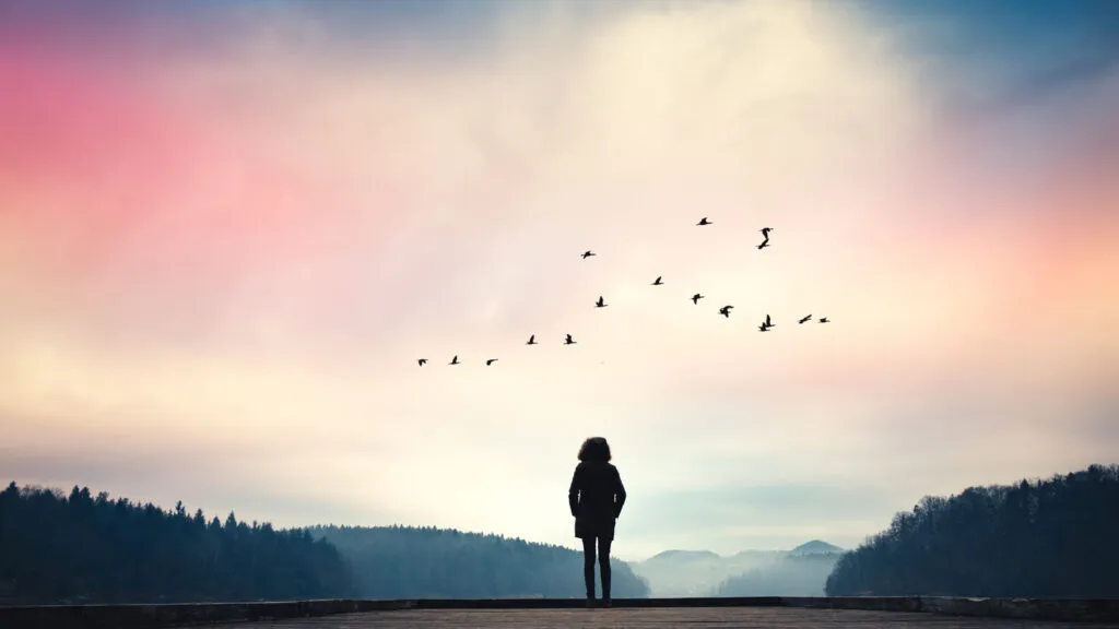 A silouette of a woman looking up at a colorful sky; Getty Images