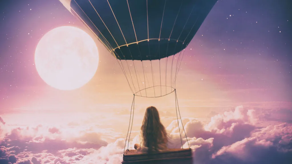 Young girl in a hot air balloon above clouds; Getty Images