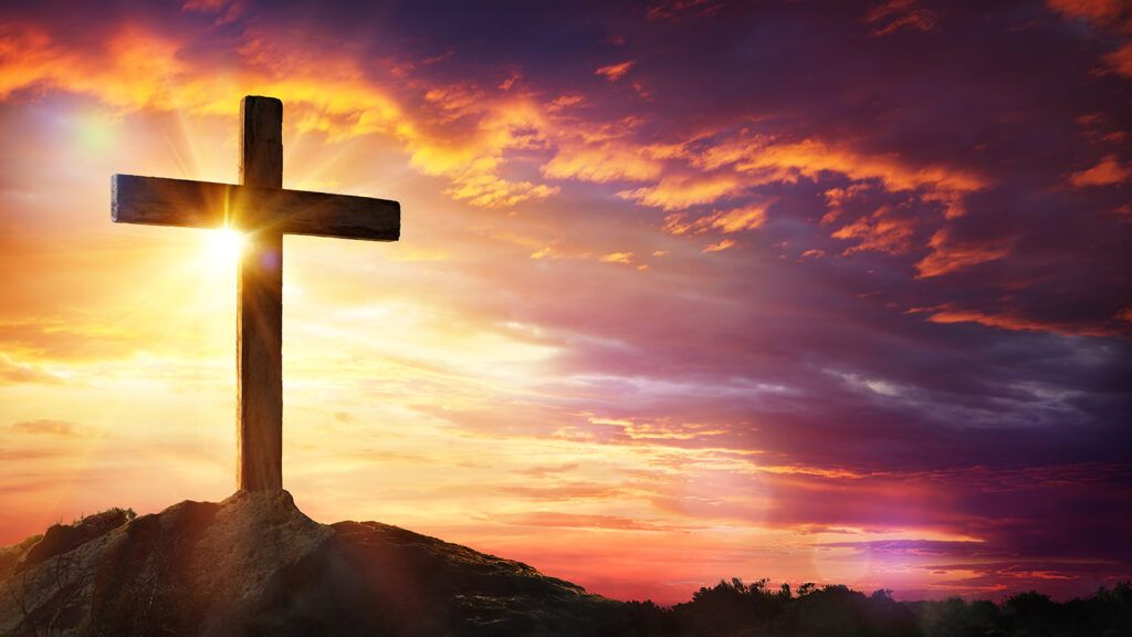 Cross at sunset with sunlight and orange clouds