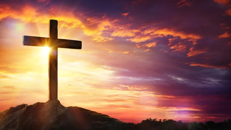 Cross at sunset with sunlight and orange clouds