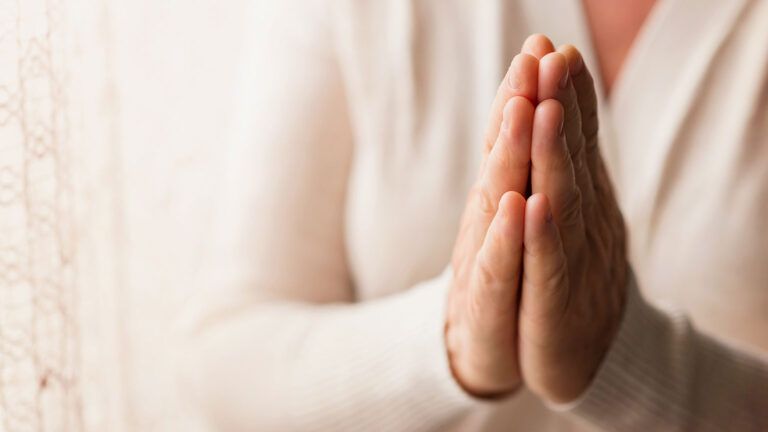 A woman's hands clasped in prayer