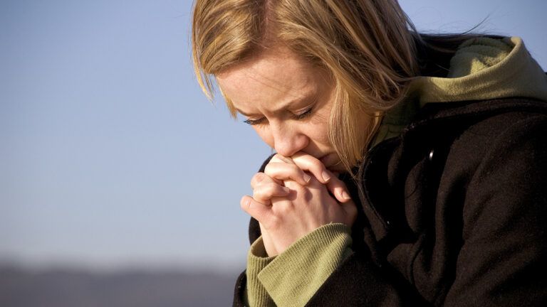 A woman bows her head in prayer