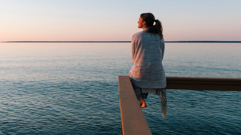 Woman sitting by a quiet lake