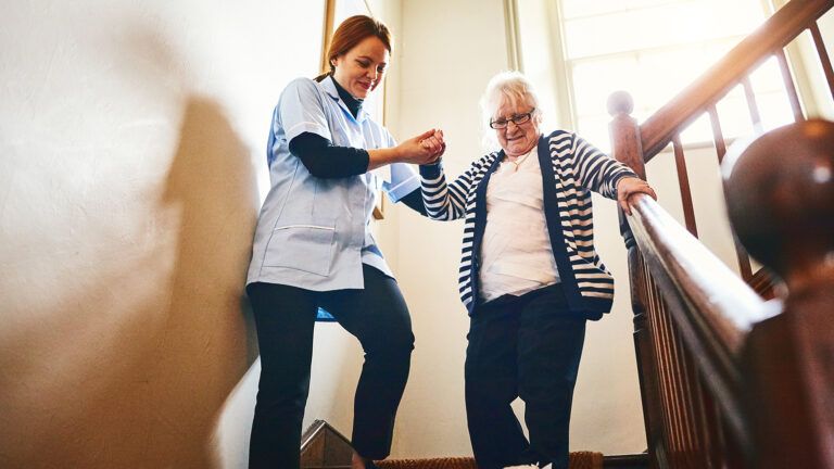 Caregiver helping senior woman down the stairs