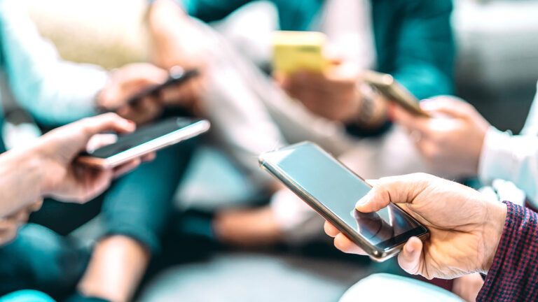 A group of people, all looking at their smartphones