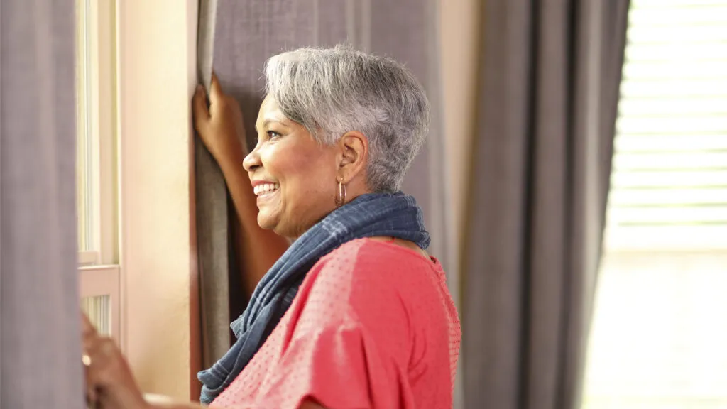 A senior woman looking out of a window; Getty Images