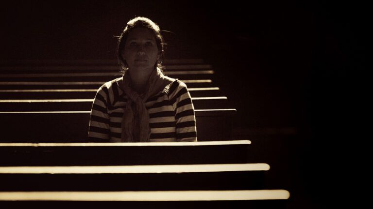 A woman prays silently alone in church