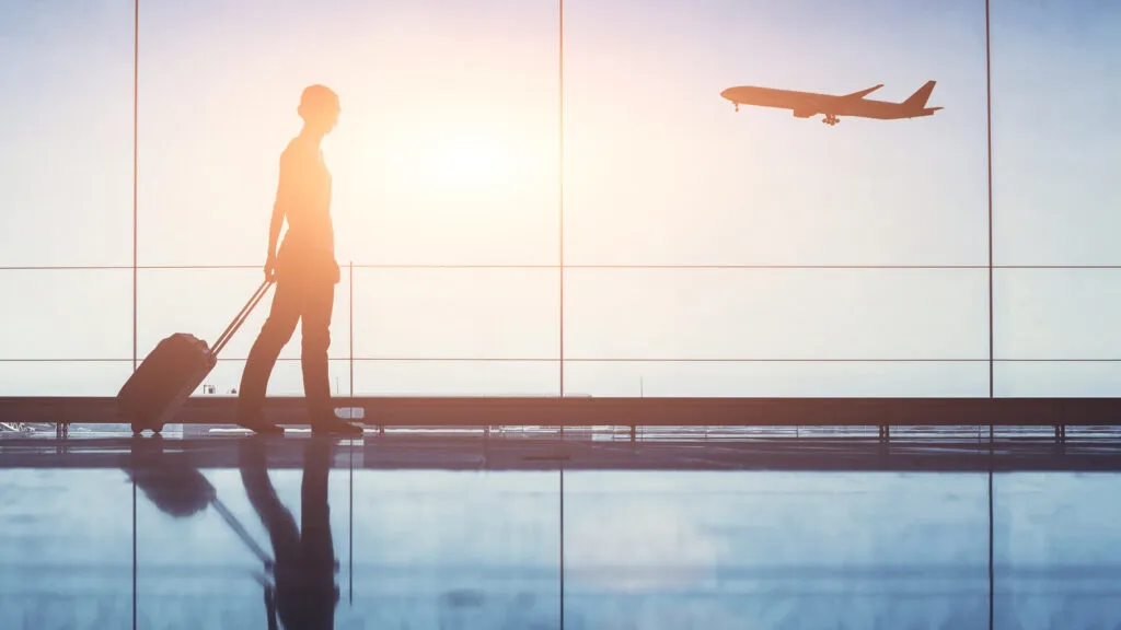 Woman walking through airport in sunlight (Getty Images)