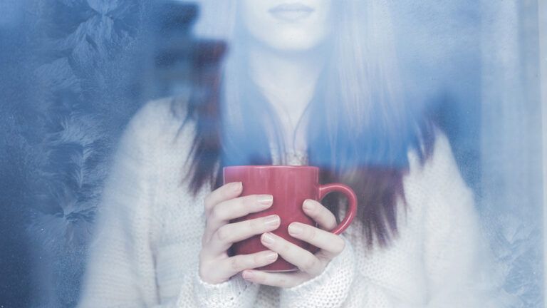 Woman holding a mug by the window