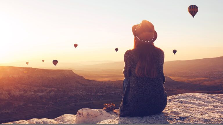 A woman watches hot air balloons float by