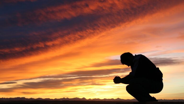 Man praying at sunset