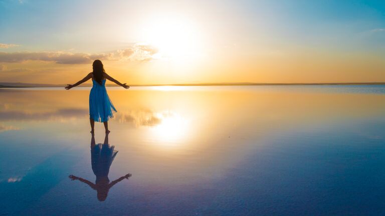 Woman stretching her arms out towards the sun