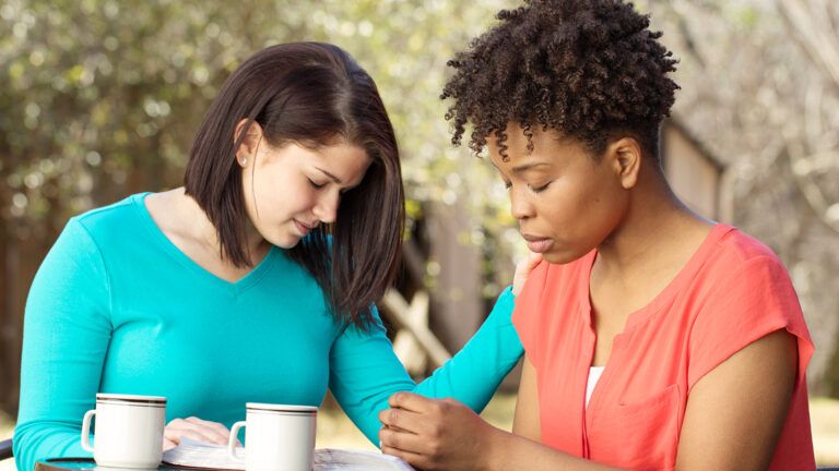 Two female friends praying together