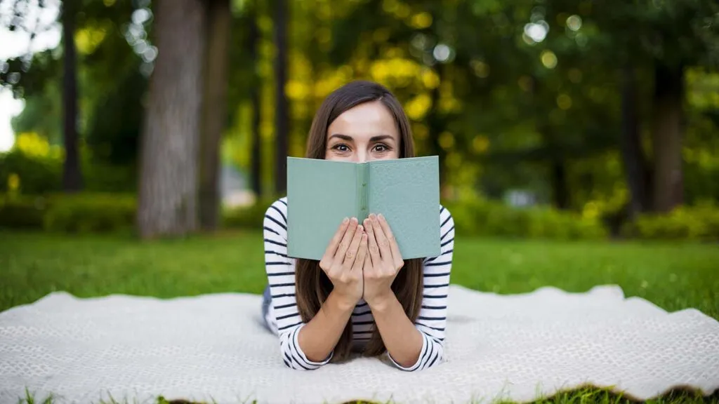 Woman reading a spring book while lying on a blanket outside