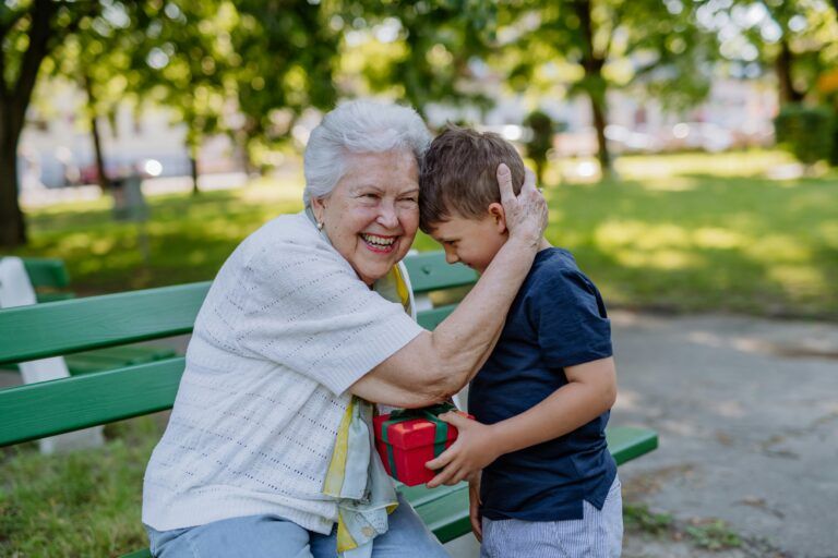 A grandchild surprised his grandmother with a gift in the park.