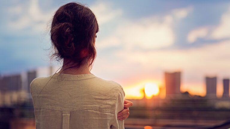 A woman gazes out at the sunrise