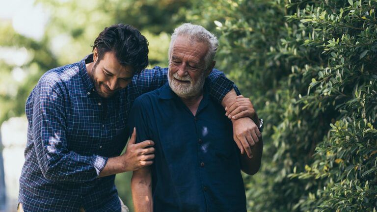 Adult son and senior father walking outside