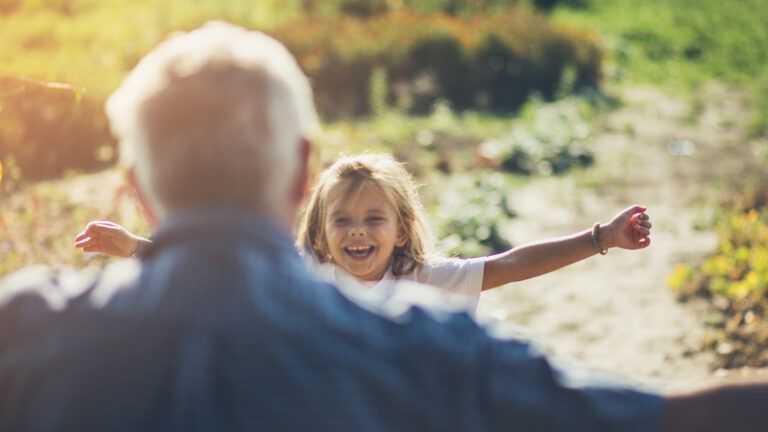 Young girl running towards her grandfather with open arms