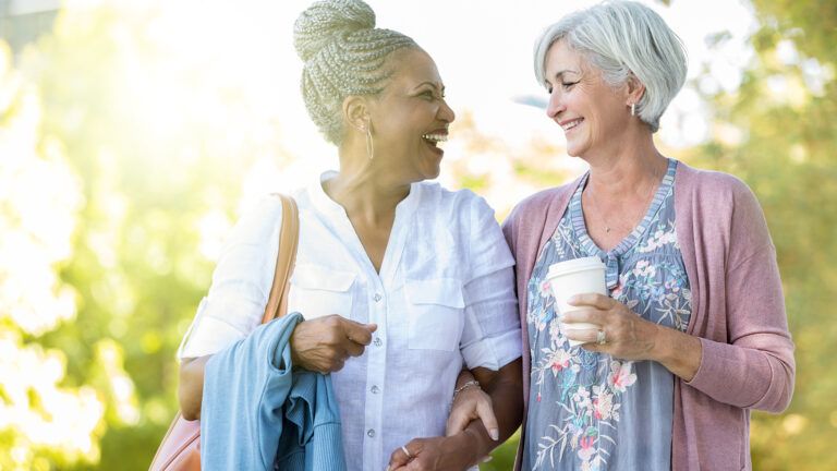 Two senior women walking arm in arm in a park