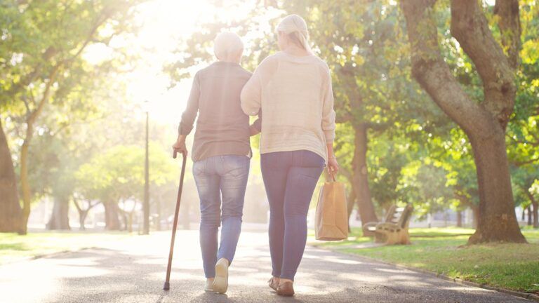 Daughter helping mother walk with a cane