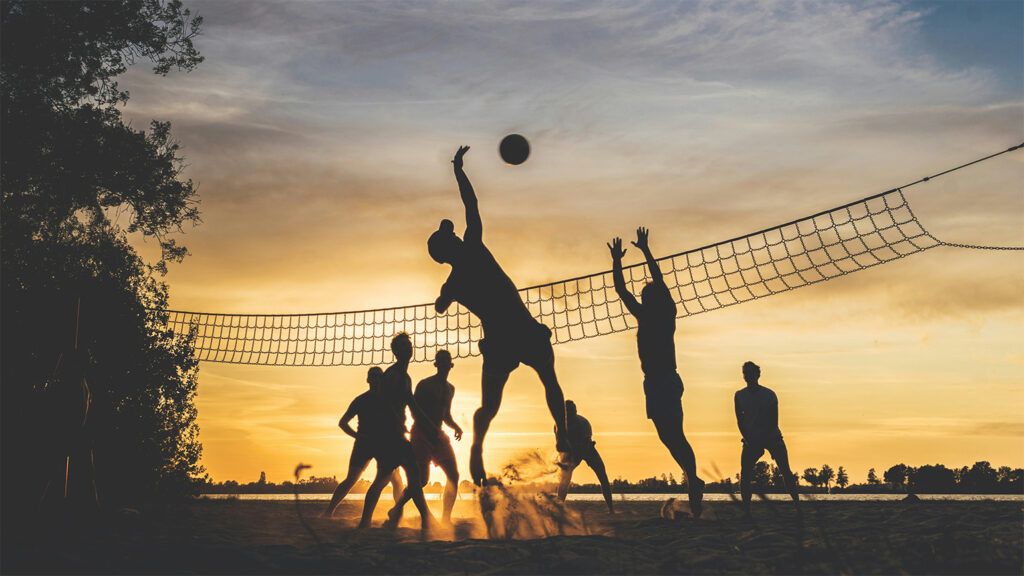 A group of friends play beach volleyball while the sun is setting. Taken on a warm summer evening in the Netherlands.