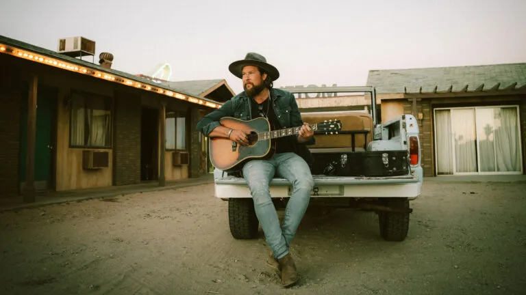 Zach Williams sitting on a pickup truck sharing his story of faith