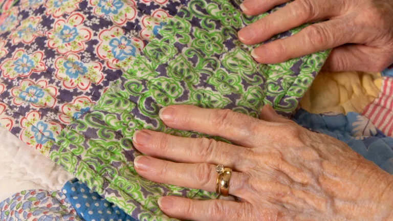 Ginger Rue's mother, Lois Griffin, holding one of her quilts; Photo by Michael A. Schawrz