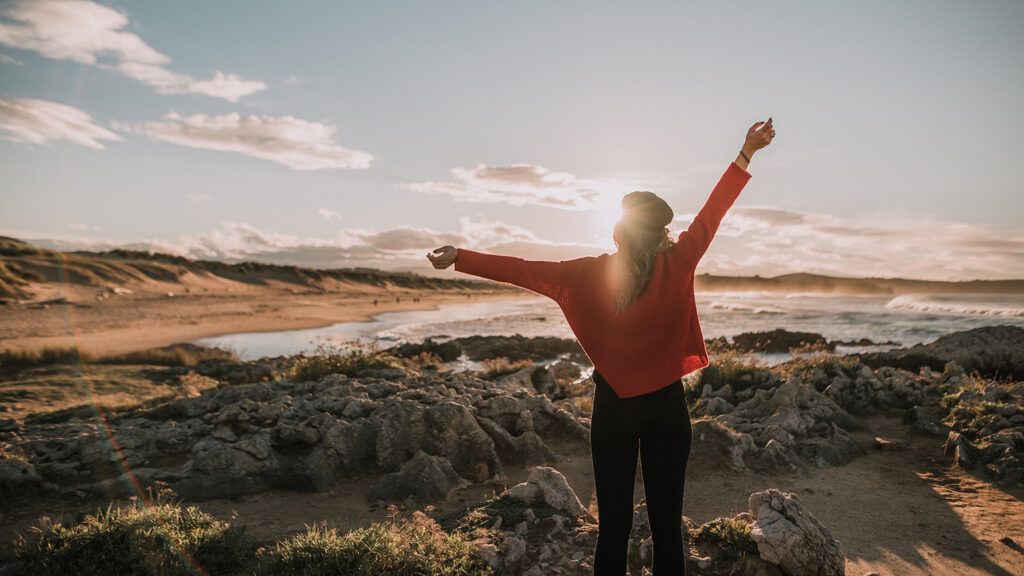 Woman with arms raised by the sea; Getty Images