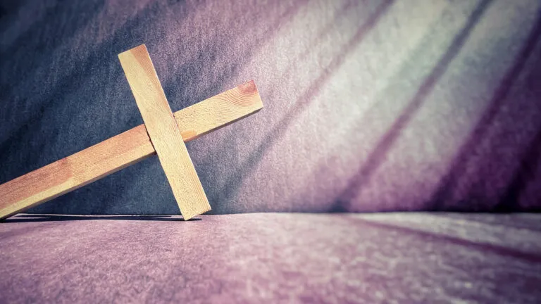 A wooden cross on a purple background showing how to read Lent Bible verses