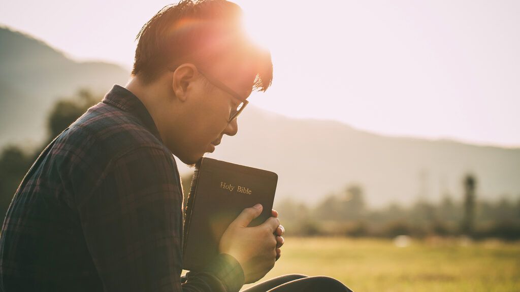 A man prays, Bible in hand, during Lent; Getty Images