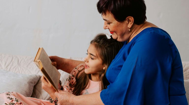 A woman reading a book to a young girl.