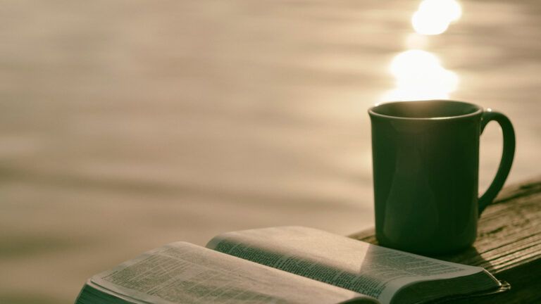 Green ceramic mug beside book.